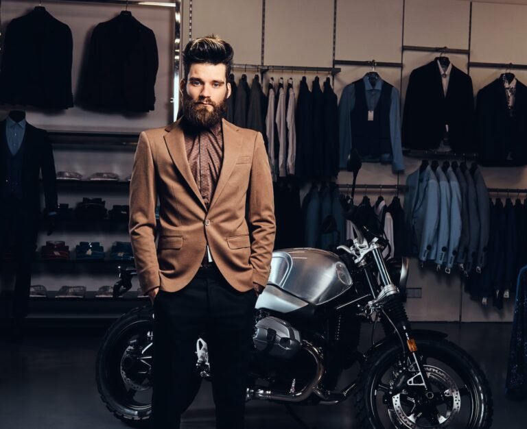 Fashionable man posing next to a retro sports motorbike at the men's clothing store.